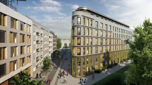 Een modern gebouw met een gebogen gevel, meerdere ramen en een voetgangersgebied met mensen en groen.