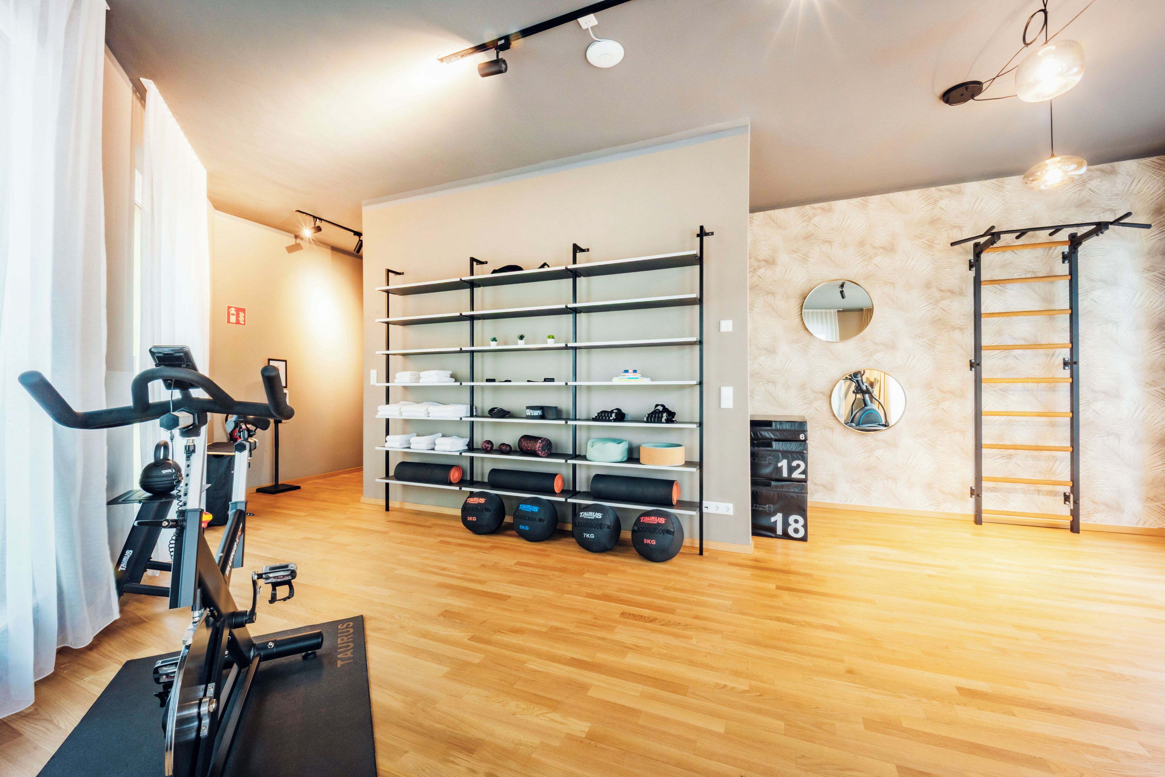 Ein Fitnessraum mit Laufband, Gewichtsständern und einer Klimmzugstange.