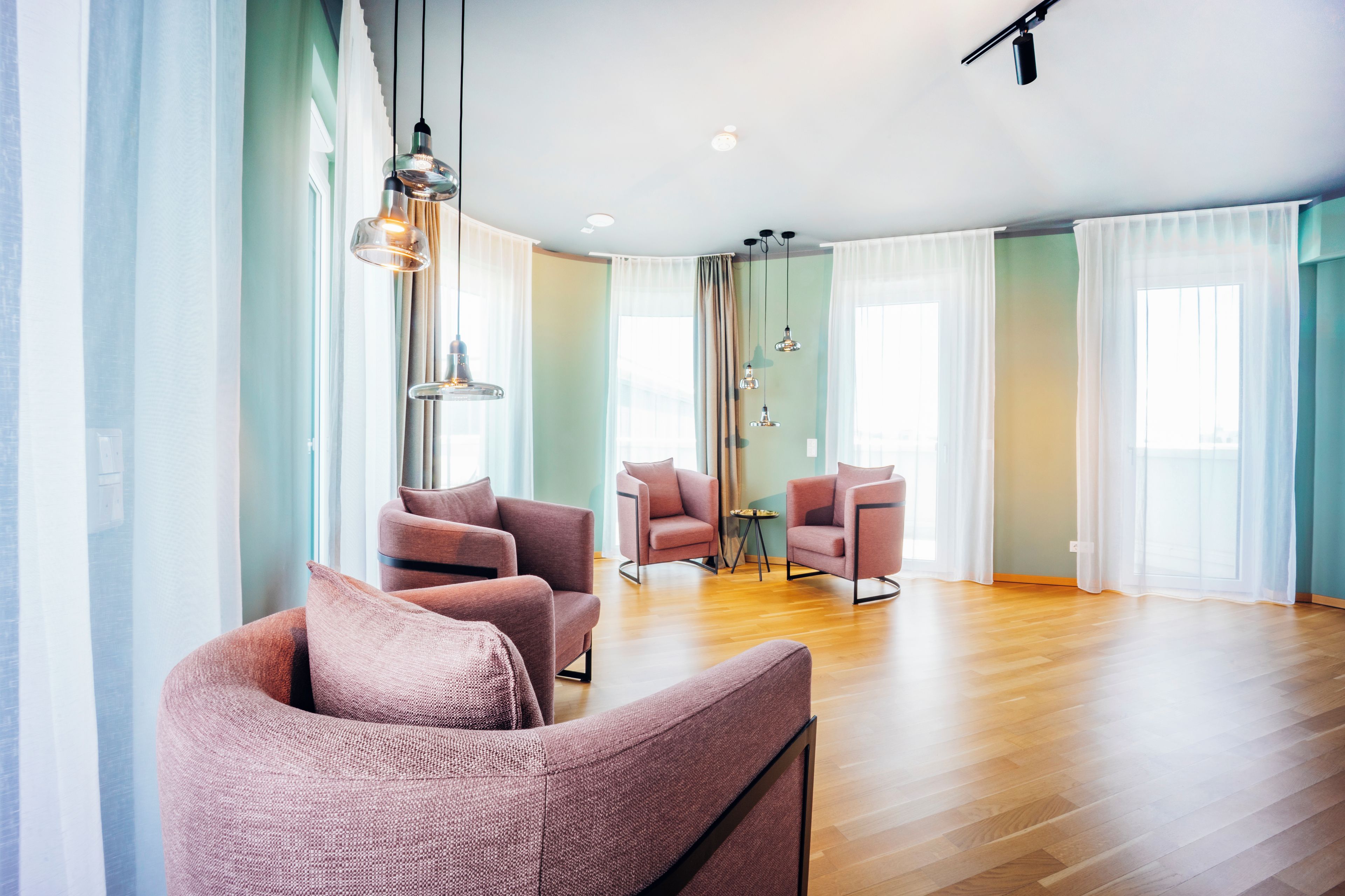 Un amplio espacio de sala con muebles modernos, ventanas grandes y piso de madera.