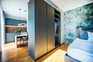 Une chambre moderne avec un lit, un bureau et un coin cuisine.