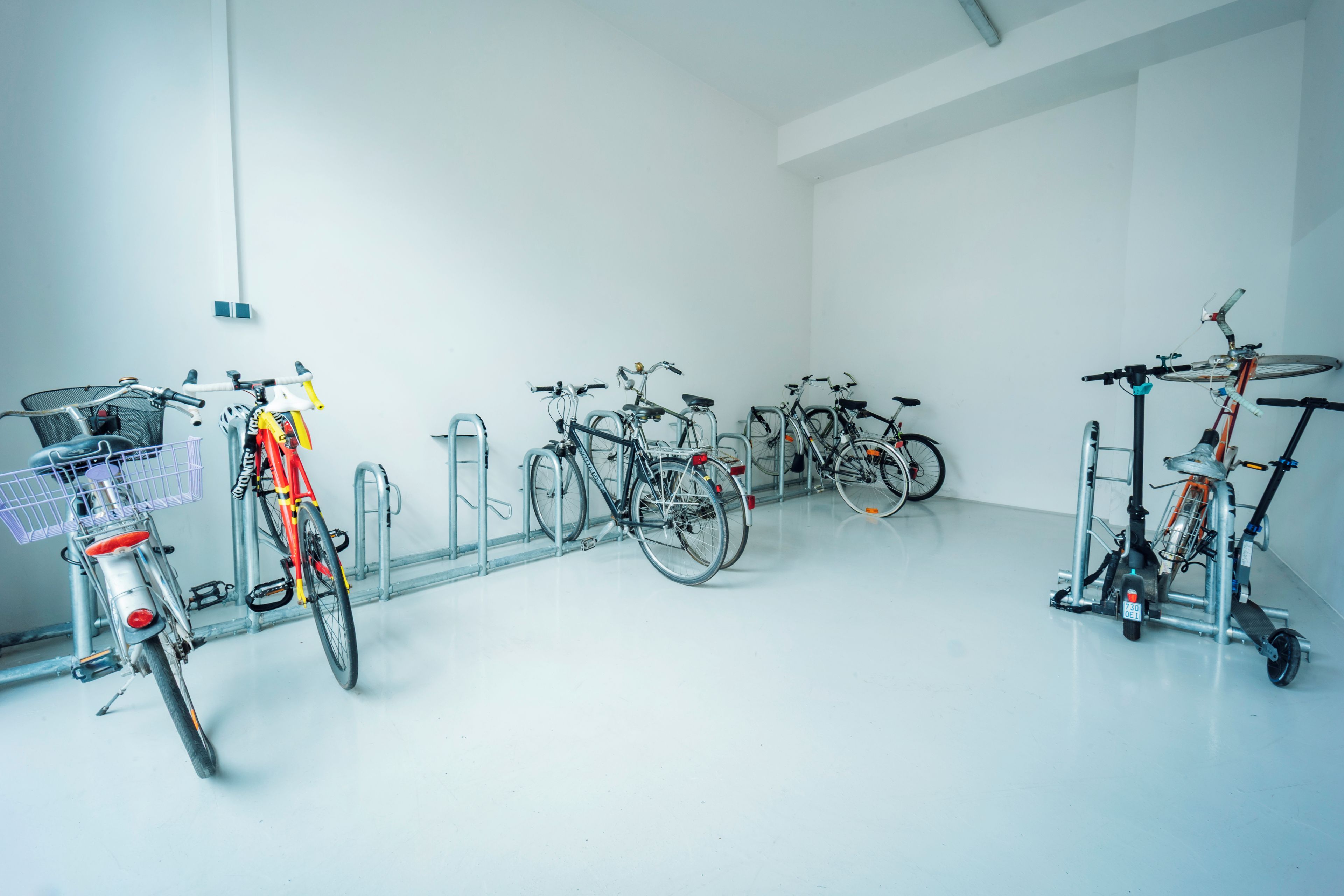 Una habitación limpia y blanca con varias bicicletas estacionadas junto a la pared.