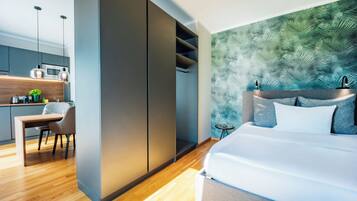 A modern bedroom with a large bed, a nightstand, and a green leaf-patterned wall.