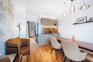 A modern kitchen with a microwave, a sink, and a wooden countertop. There is a dining area with a table and chairs. - Brera Serviced Apartments Ulm (Ulm)