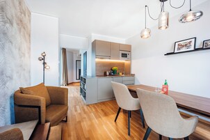 Una cocina moderna con microondas, un lavamanos y una encimera de madera. Hay un comedor con una mesa y sillas.