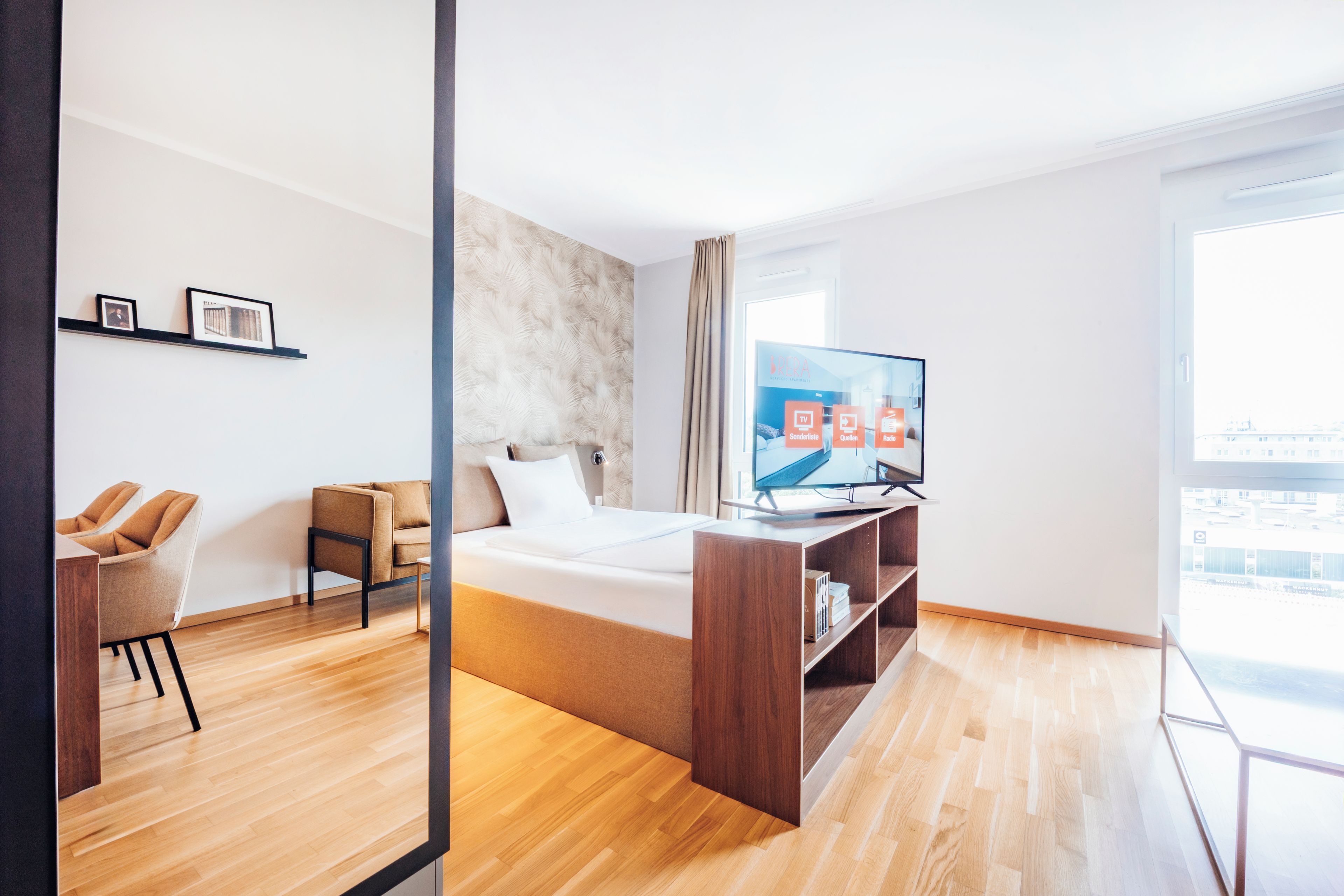 Ein modernes Hotelzimmer mit Bett, Fernseher, Schreibtisch und Stuhl.