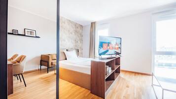 Ein modernes Hotelzimmer mit Bett, Fernseher, Schreibtisch und Stuhl.