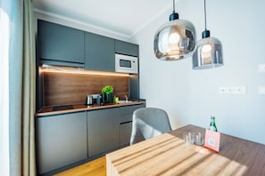 A compact kitchen with modern appliances, a dining table with a placemat, and pendant lighting. - Brera Serviced Apartments Ulm (Ulm)