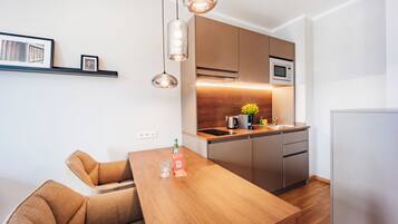 A modern kitchen with a wooden dining table, built-in appliances, and pendant lighting.