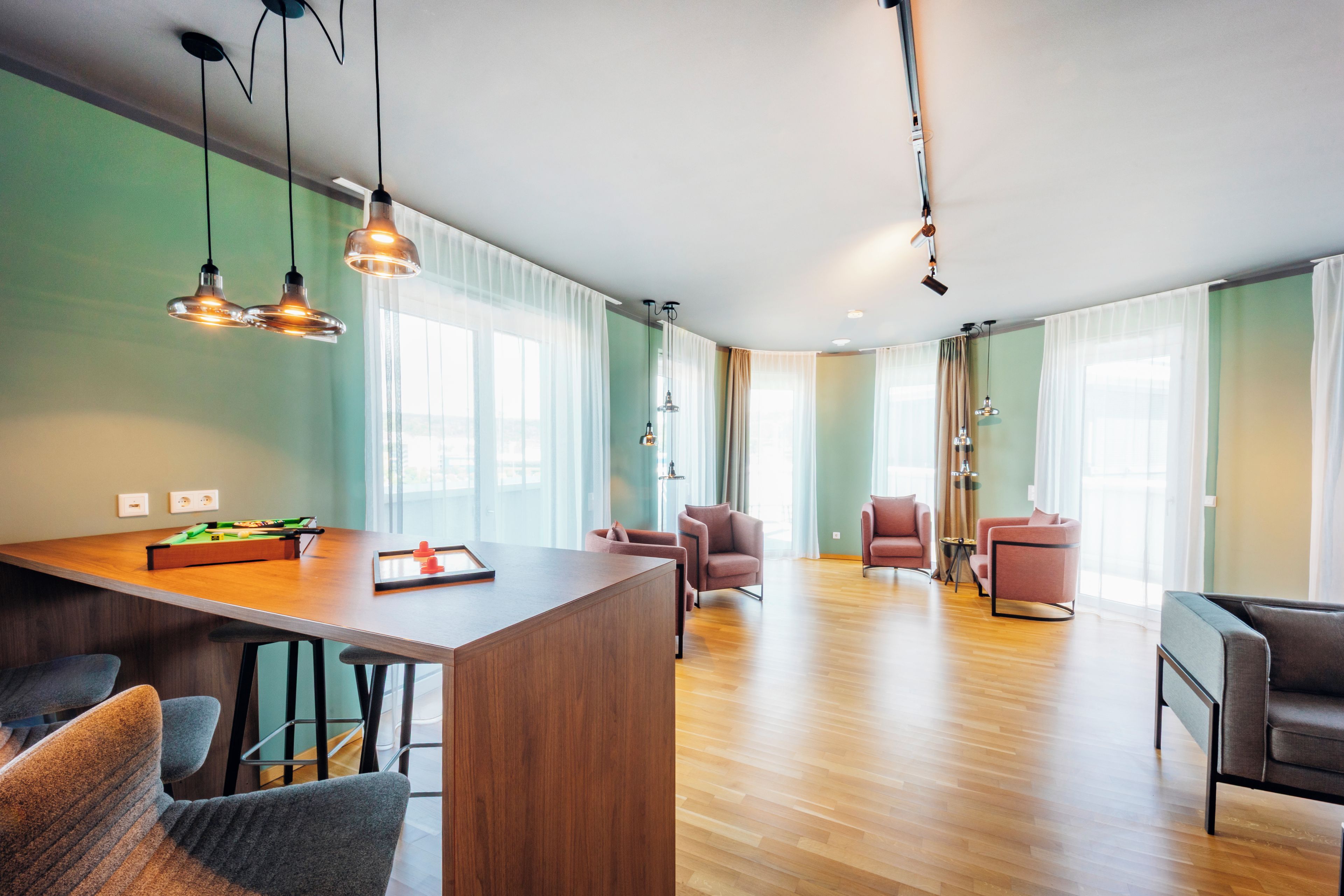 A modern living room with a wooden floor, a dining area with a wooden table, and a seating area with chairs.