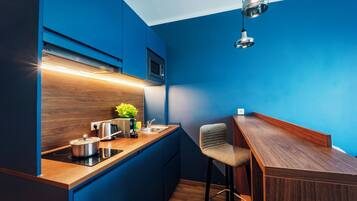 A compact kitchen with a wooden countertop, a built-in microwave, and a stainless steel kettle.