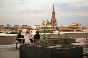 A rooftop terrace with seating and a view of a historic cathedral. - Brera Serviced Apartments Ulm (Ulm)