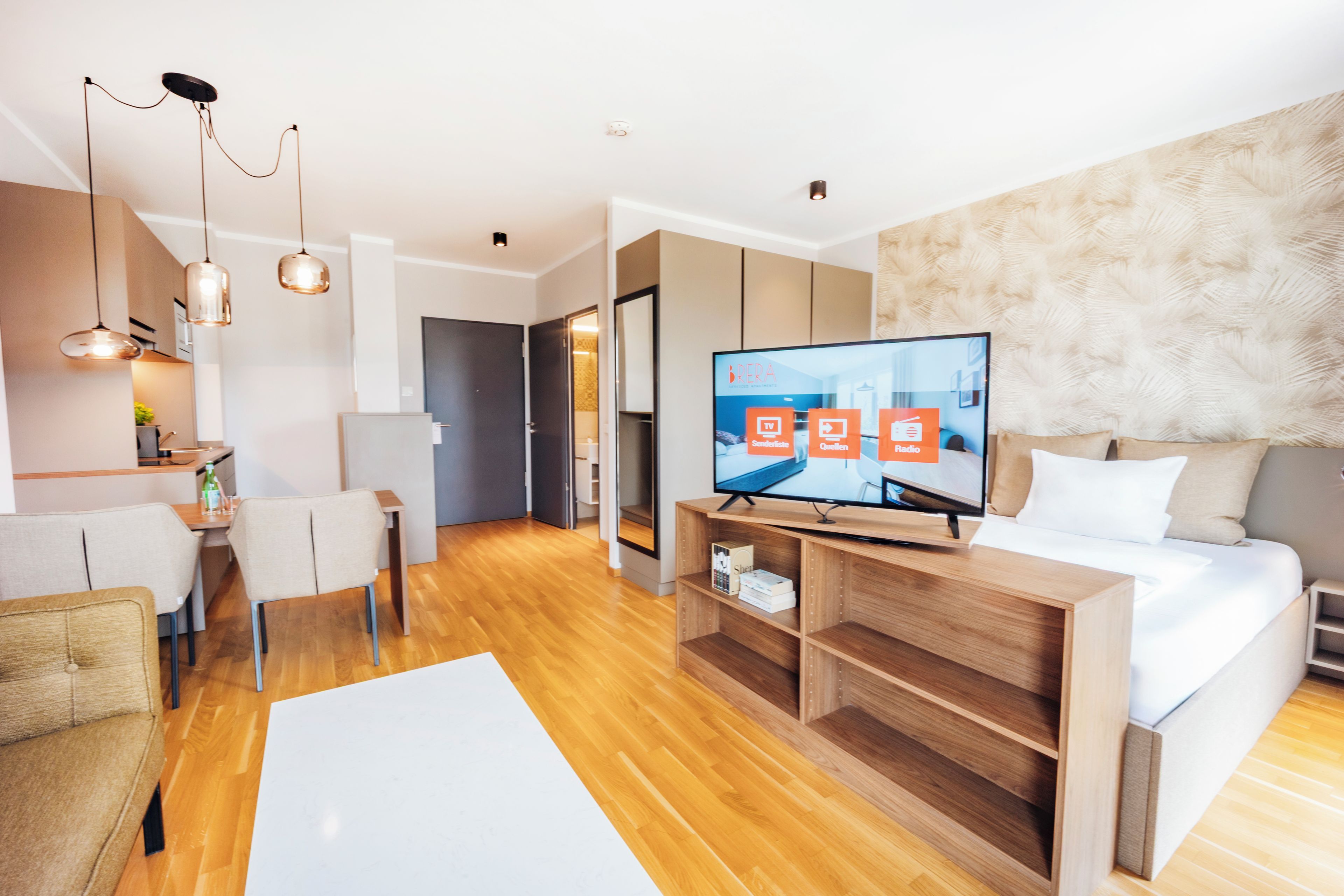 A modern hotel room with a flat-screen TV, wooden furniture, and a large bed.