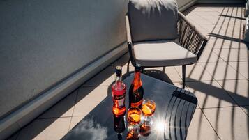 A rooftop terrace with a table, two chairs, and a bottle of Aperol with glasses.