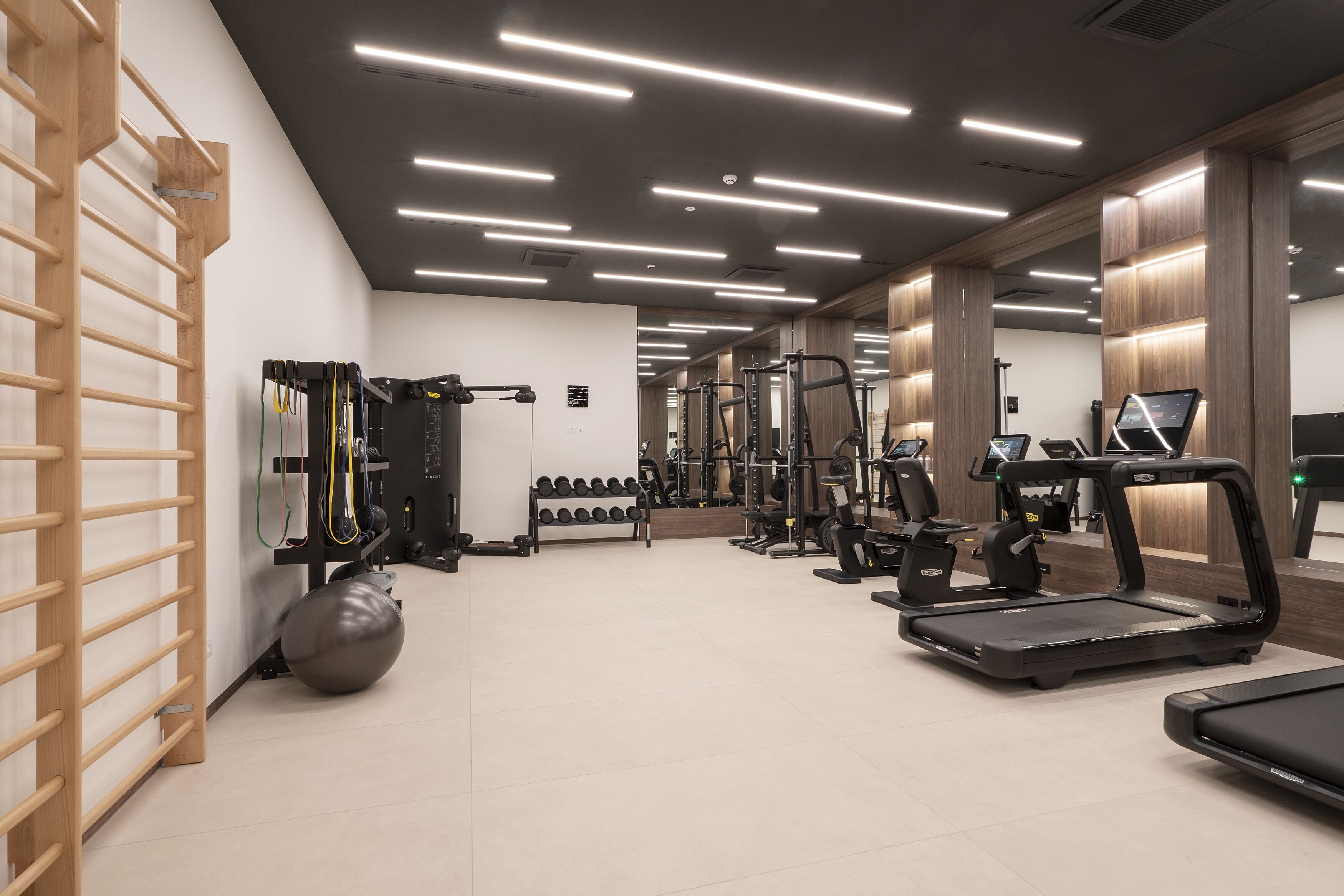 Een moderne sportschool met loopbanden, krachttrainingsapparaten en diverse gewichten.
