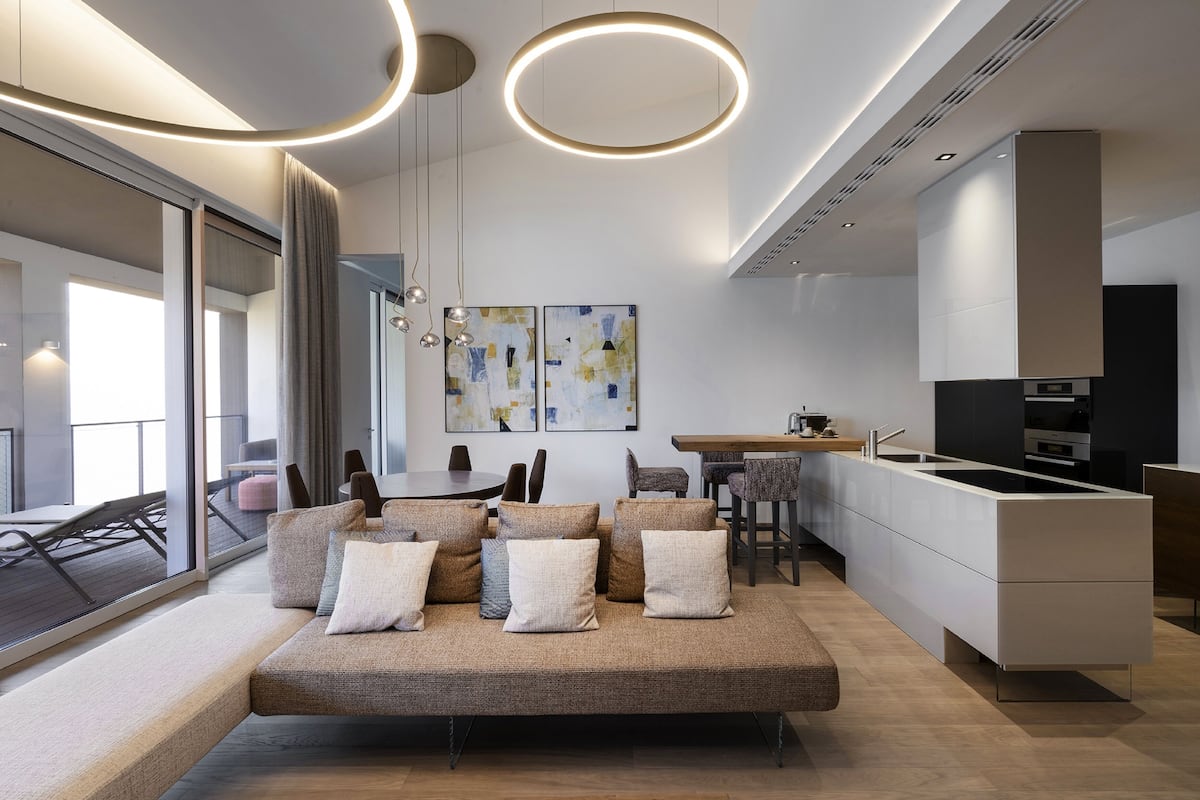 A modern living room with a sofa, a dining area, and a kitchen.