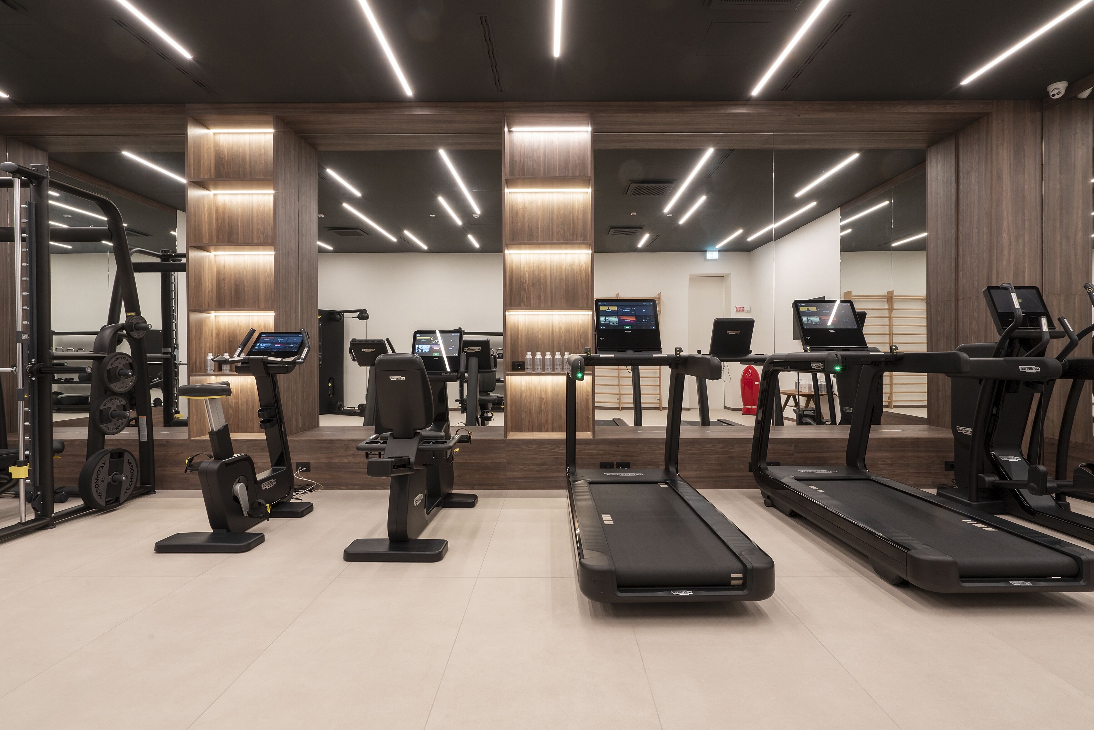 Una palestra moderna con tapis roulant, ellittiche e attrezzature per l'allenamento con i pesi.