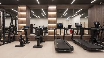 Una palestra moderna con tapis roulant, ellittiche e attrezzature per l'allenamento con i pesi.