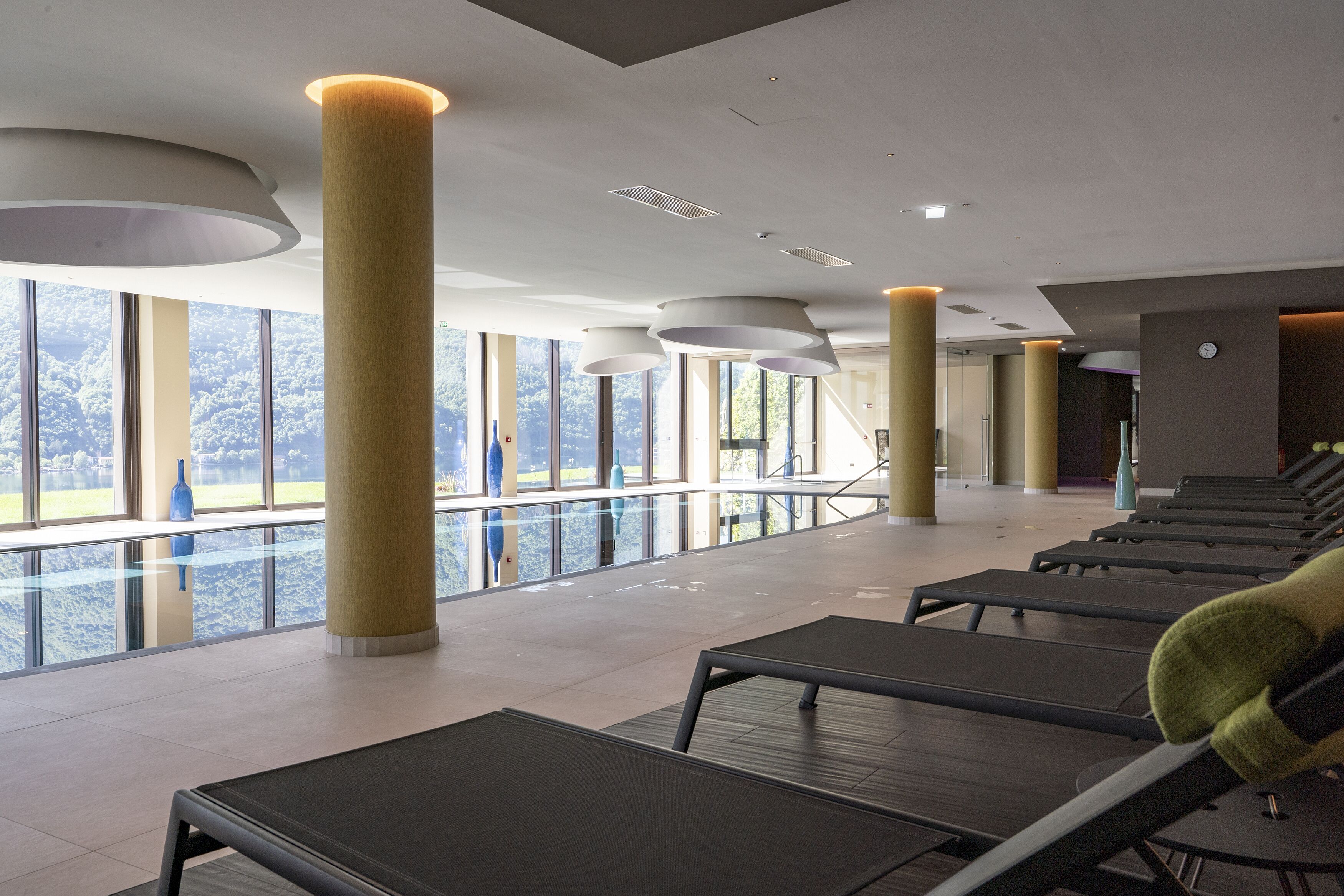 A modern indoor relaxation area with sun loungers, large windows, and a view of a snowy landscape.