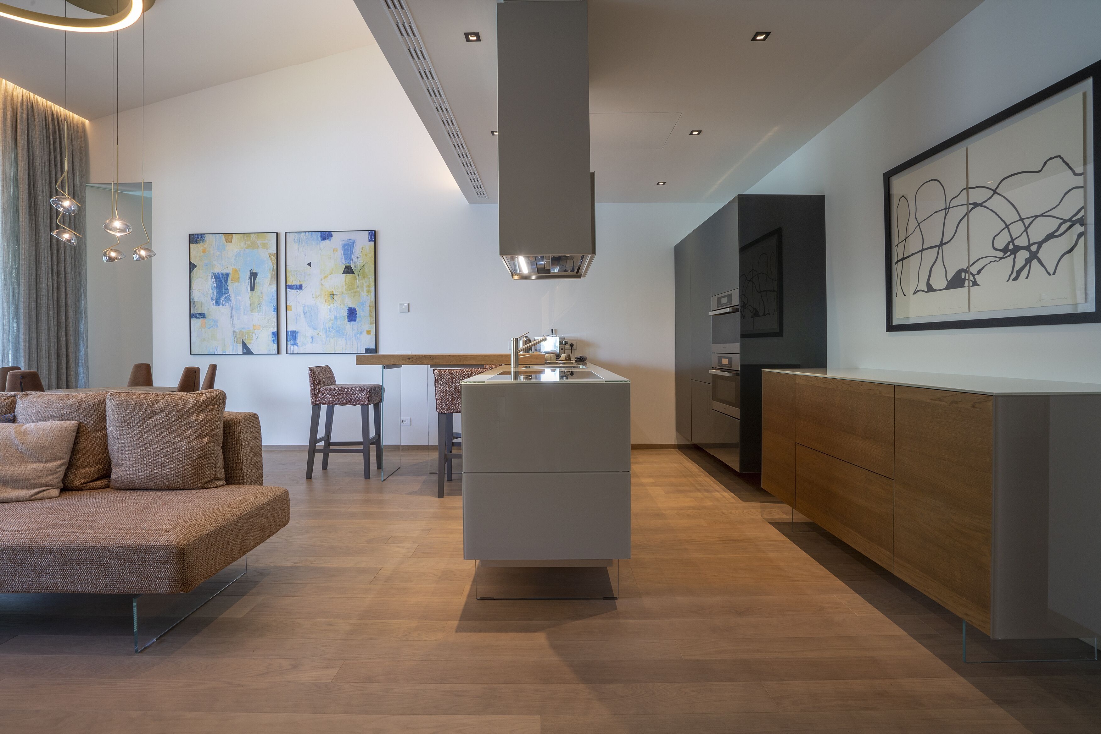 Een moderne keuken met een centraal eiland, een zithoek met een bank en kunstwerken aan de muren.
