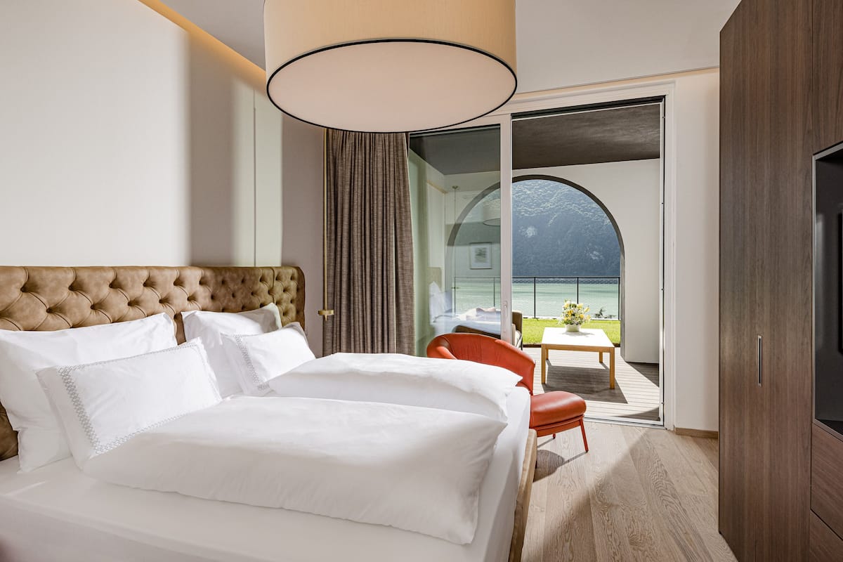 A hotel room with a large bed, a television, and a balcony with a view of the water.