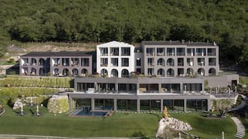 Un hotel moderno con diversi edifici, ampie vetrate e un giardino curato con zone relax.