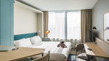 Una camera d'albergo con un letto, una scrivania, una sedia, un computer portatile e una televisione.