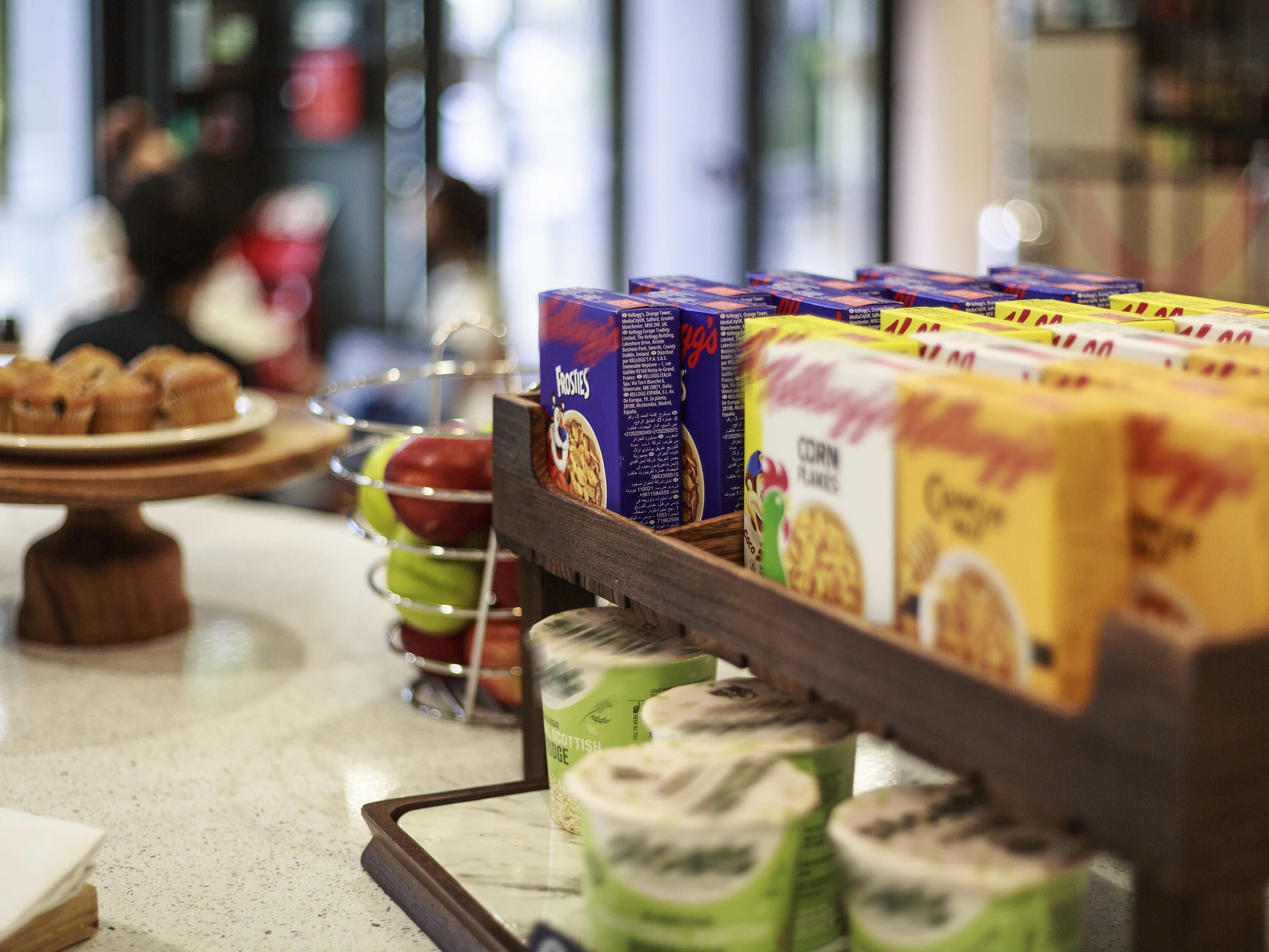 A breakfast display with various cereals and a plate of muffins.