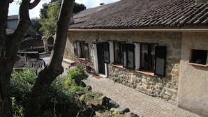 A stone building with a tiled roof, stone walls, and windows with shutters.
