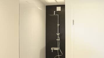 Een moderne badkamer met een douchecabine van glas, een zwarte wand en een witte deur.