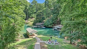 A lakeside lodge with a dock, a small pavilion, and a fire pit area surrounded by lush greenery. - Lake Pleasant - Lakefront, Private Dock, Game room (Huddleston)