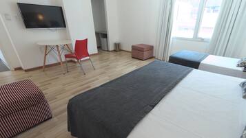 Una habitación de hotel con cama, televisión, escritorio, silla y ventana.