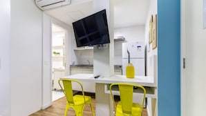 A compact kitchen with a flat-screen TV, white cabinets, and two yellow chairs. - AV1110 - Studio 4 guests Avanhandava Street (São Paulo)