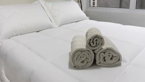 A neatly made bed with white bedding and rolled towels. - AV1110 - Studio 4 guests Avanhandava Street (São Paulo)