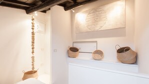 A minimalist room with a white wall, a wooden ceiling, and a shelf with woven baskets.