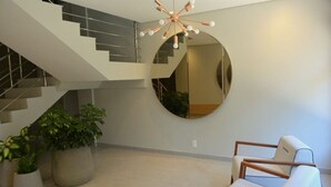 Un intérieur moderne avec un escalier, un miroir rond et un coin salon.