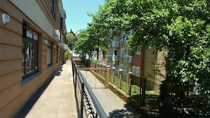 A narrow urban pathway flanked by buildings with balconies and railings, leading to a gated area with greenery. - Locar-in Gramado - Aconchego Coração de Gramado (Gramado)
