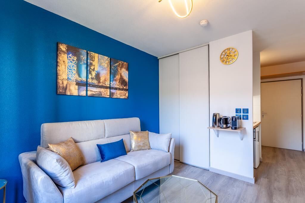 Un salón moderno con una pared azul decorativa, un sofá blanco y una mesa de centro de vidrio.