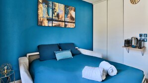 A bedroom with a bed, blue walls, a painting, a clock, and a shelf with items. - "Lumières", downtown Lyon, University of Medicine/Lyon 3, metro 200 m away, wifi (Lyon)