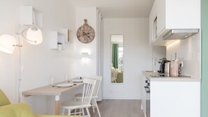 Eine moderne Küche mit weißen Schränken, einem Essbereich mit Tisch und Stühlen sowie einer großen Wanduhr.