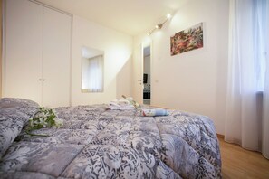 A bedroom with a large bed, a mirror, a painting, and a door.