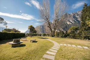 A park with a stone path, benches, and a mountain backdrop.
