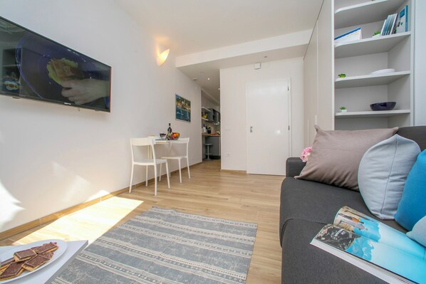 A modern living room with a sofa, a coffee table, and a TV mounted on the wall.