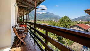 A balcony with wooden railings, a table, and chairs, overlooking a mountainous landscape. - Casa Alla Grotta (Arco)