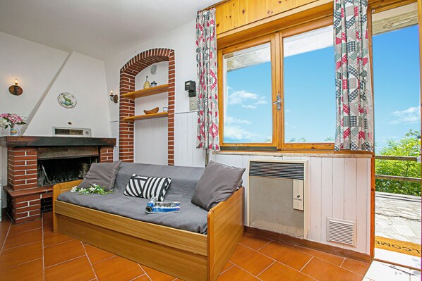 Een gezellige woonkamer met een bank, open haard en een raam met gordijnen.