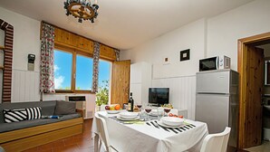 A compact kitchen with a dining area, a sofa, and a television.