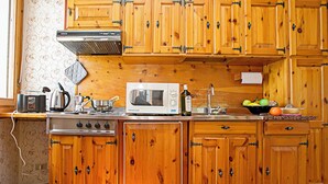 Une cuisine avec des meubles de rangement en bois, une cuisinière, un four à micro-ondes et divers ustensiles de cuisine disposés sur le plan de travail.