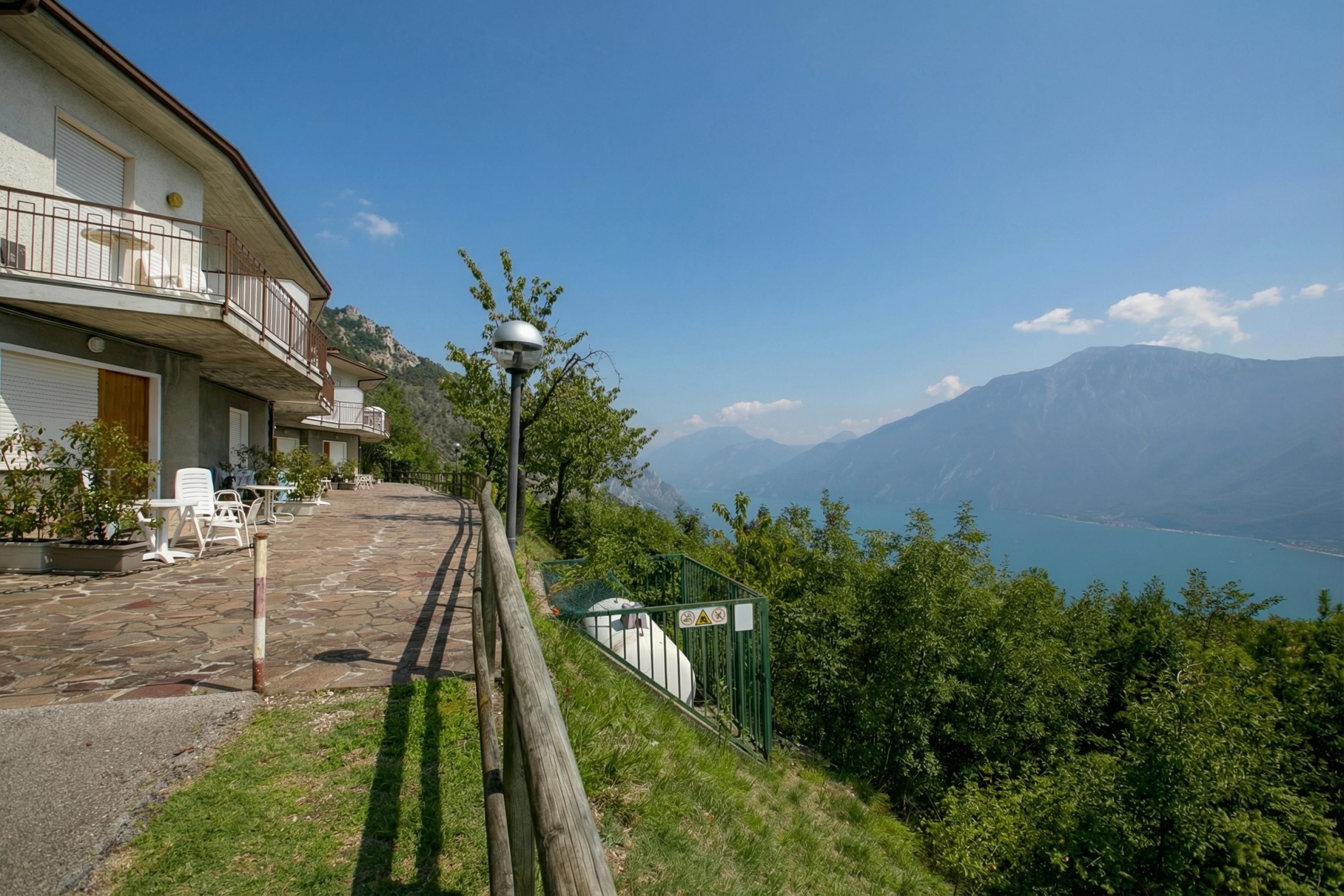 Un bâtiment doté d’une terrasse, offrant une vue sur un lac et avec une montagne en arrière-plan.