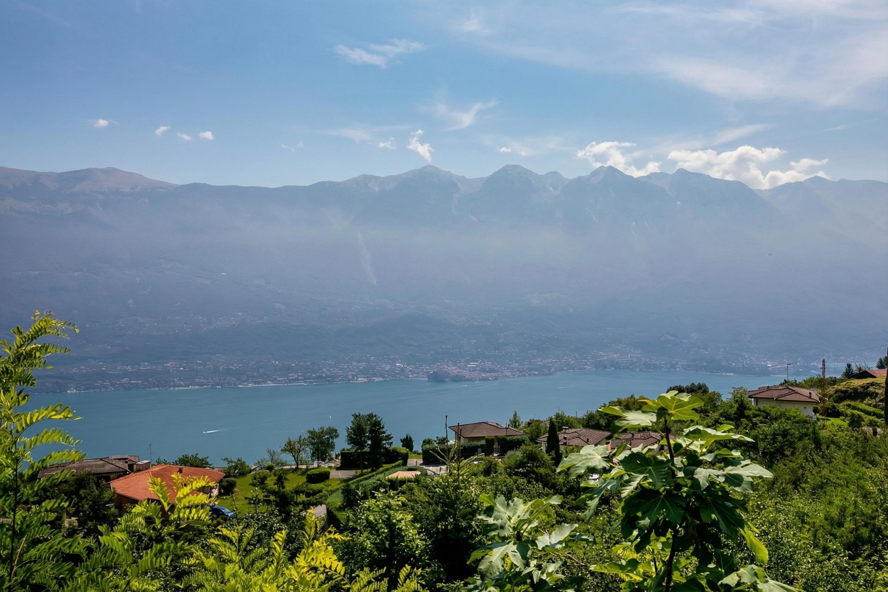 A mountainous landscape with a lake, houses, and greenery.