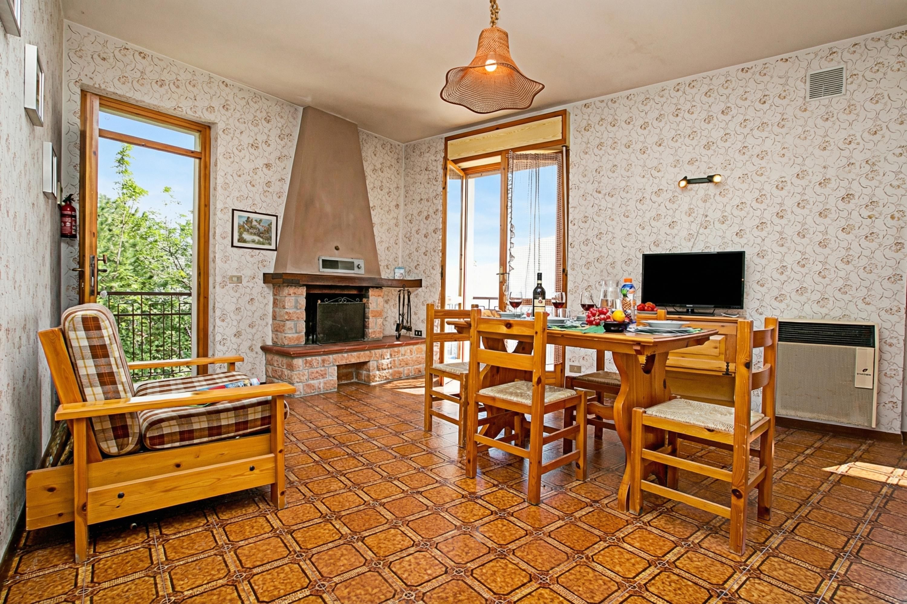 A cozy room with a fireplace, a dining table with chairs, a sofa, and a TV.