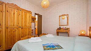 Une pièce comprenant un lit, une armoire en bois, un miroir et un luminaire suspendu.